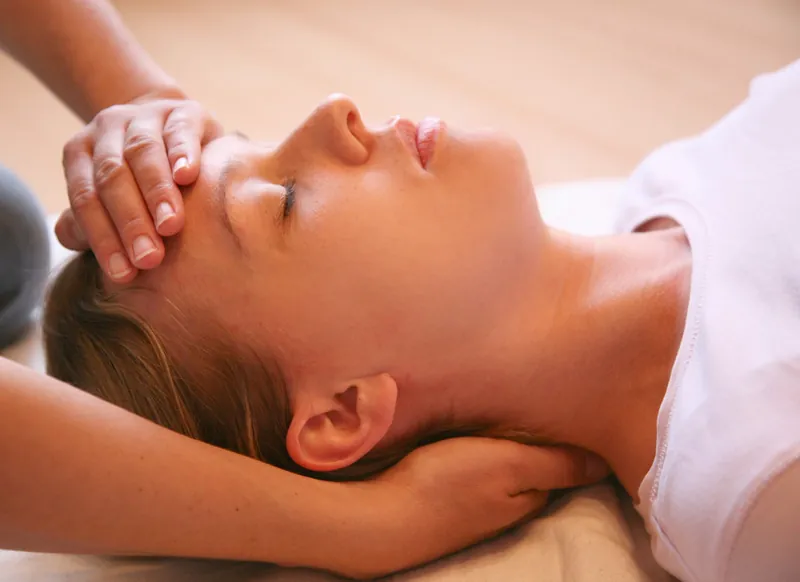 Practitioner gently holding points on a relaxed client's head