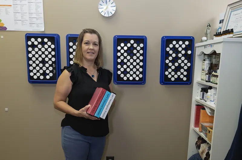 Jennifer in her testing room holding MFT test-vial kits, with vial racks on the wall
